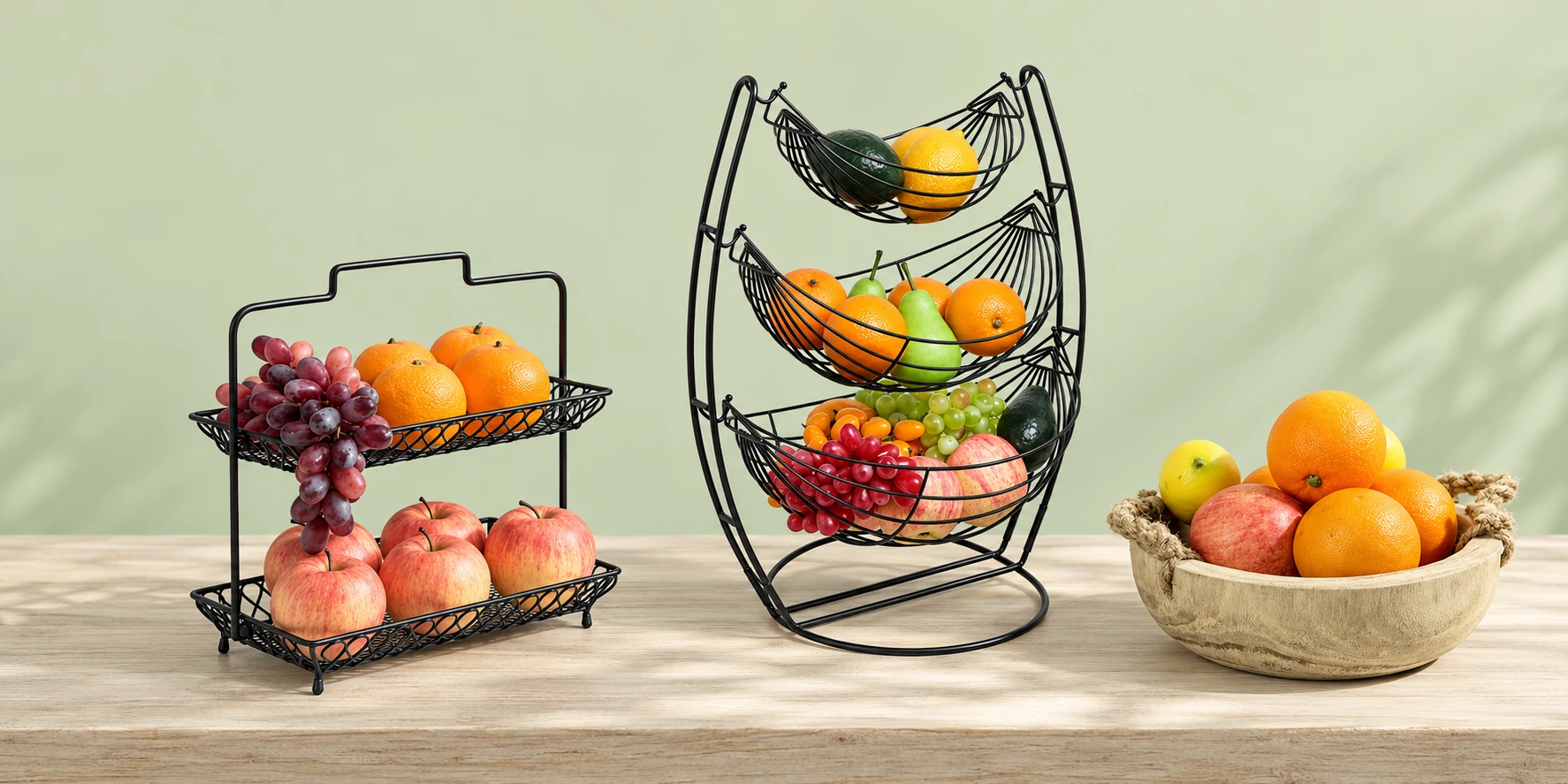 Three-tier black hammock rack, handled wire fruit basket and wooden rope-handle bowl arranged on a kitchen counter